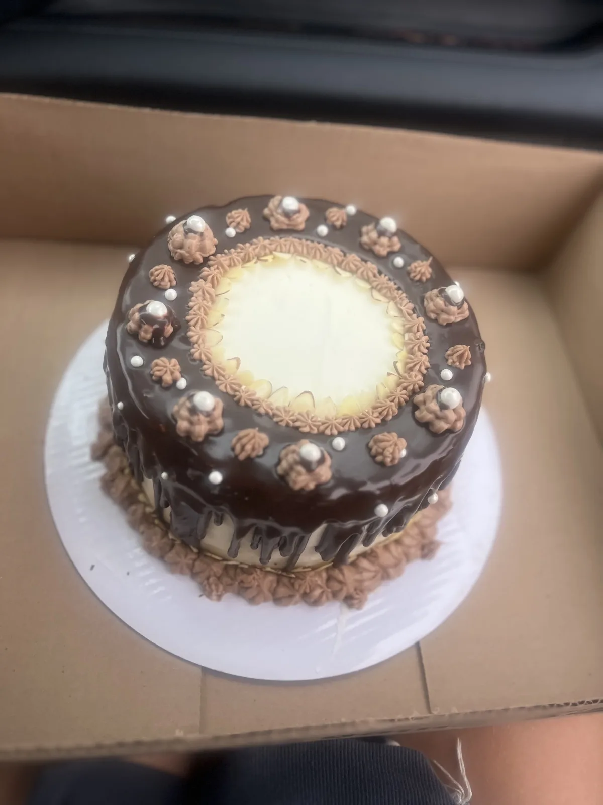 Chocolate ganache drip cake ringed with sliced almonds and sugar pearls