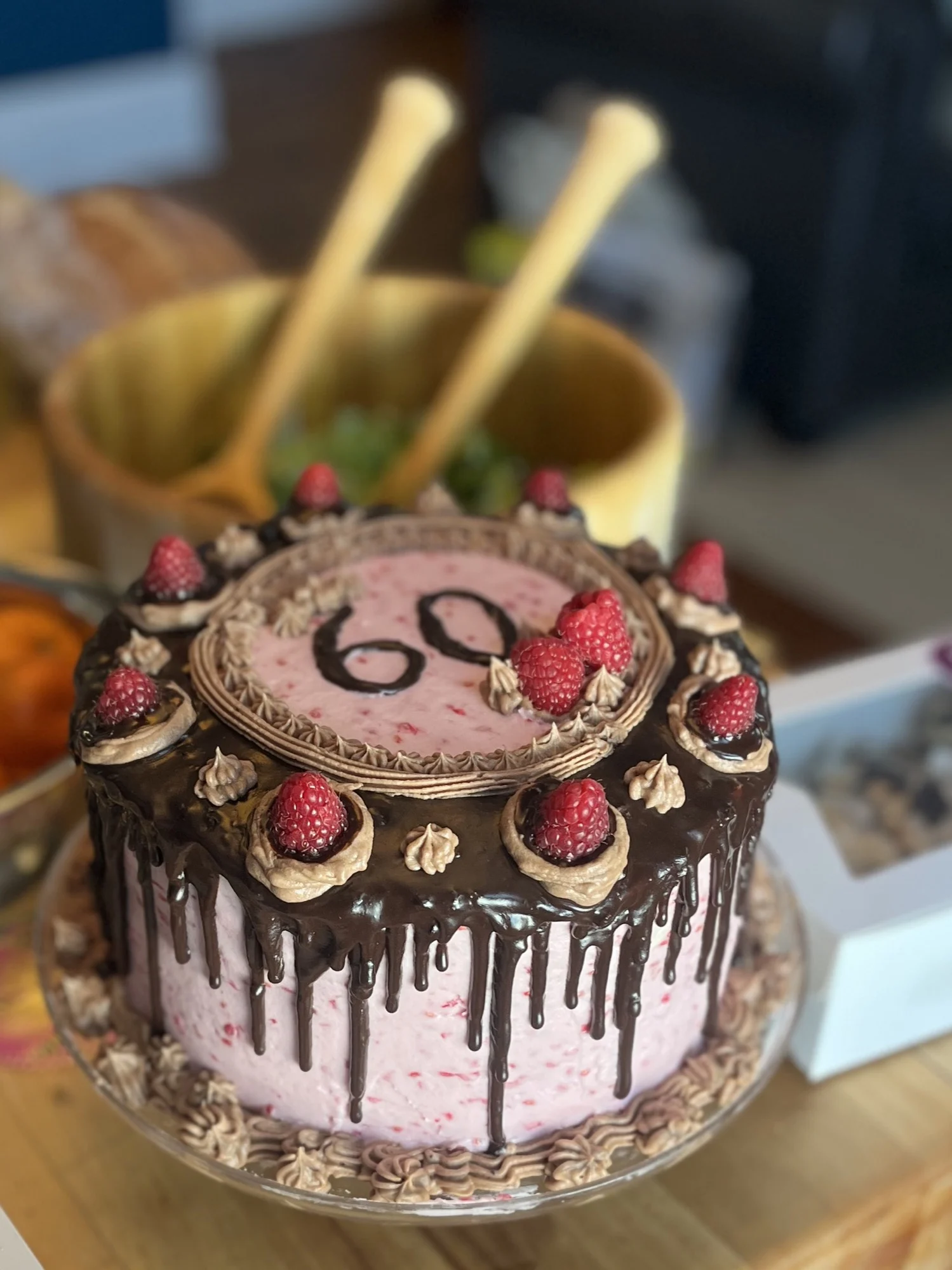 Chocolate ganache drip cake with raspberry buttercream, fresh raspberries, and a '60' piped on top