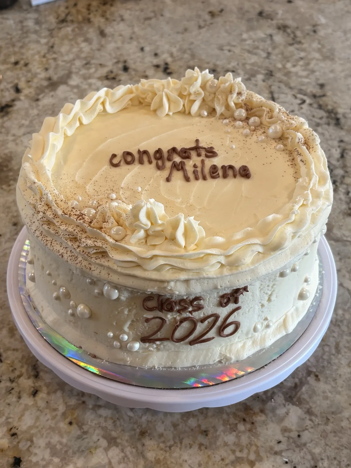 Two mascarpone cakes dusted with cocoa, piped with 'congrats Milena' and 'Class of 2026'